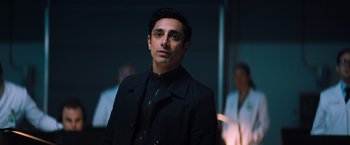 Movie still from “Venom” (2018), directed by Ruben Fleischer – A man wearing a black jacket standing in a dark room; Close Up shot, Over the shoulder angle