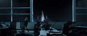 Movie still from “Venom” (2018), directed by Ruben Fleischer – A woman walking past a table with a laptop on top of it; Extreme Wide shot, Over the shoulder angle