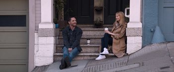 Movie still from “Venom” (2018), directed by Ruben Fleischer – A man and a woman sitting on steps holding coffee cups; Wide shot, High angle