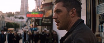 Movie still from “Venom” (2018), directed by Ruben Fleischer – A person with a crowd of people in the background; Close Up shot, Over the shoulder angle