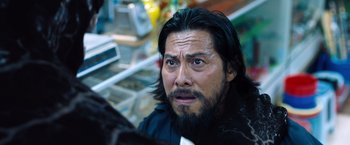 Movie still from “Venom” (2018), directed by Ruben Fleischer – A person with long hair and a beard; Close Up shot, Over the shoulder angle