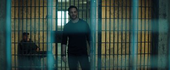 Movie still from “Venom” (2018), directed by Ruben Fleischer – A man standing in front of a jail cell holding a cell phone; Medium shot, Low angle