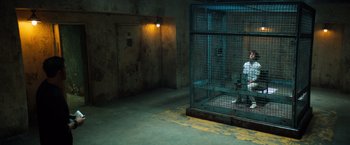 Movie still from “Venom” (2018), directed by Ruben Fleischer – A jail cell with a light on the wall; Wide shot, High angle