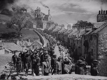 Movie still from “How Green Was My Valley” (1941), directed by John Ford – A black and white photo of a crowd of people walking down a street; Extreme Wide shot, High angle