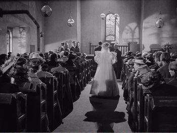 Movie still from “How Green Was My Valley” (1941), directed by John Ford – A black and white photo of a bride and groom walking down the aisle; Wide shot, High angle