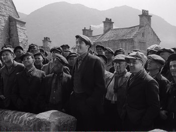Movie still from “How Green Was My Valley” (1941), directed by John Ford – A group of men standing next to each other in front of a building; Wide shot, High angle