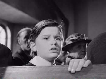 Movie still from “How Green Was My Valley” (1941), directed by John Ford – A young boy is looking at the camera while an older man looks on; Medium shot, Over the shoulder angle