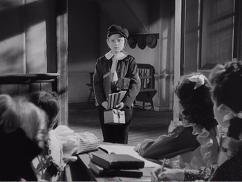 Movie still from “How Green Was My Valley” (1941), directed by John Ford – A young boy in a uniform holding a bunch of books in his hands; Medium shot, High angle