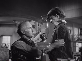 Movie still from “How Green Was My Valley” (1941), directed by John Ford – An older man and a young boy are looking at a kerosene lamp; Medium shot, Low angle