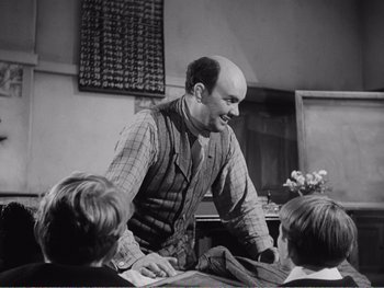 Movie still from “How Green Was My Valley” (1941), directed by John Ford – A man standing in front of a group of children; Medium shot, Over the shoulder angle