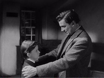 Movie still from “How Green Was My Valley” (1941), directed by John Ford – A man and a young boy standing next to each other in a room; Medium shot, Over the shoulder angle