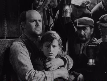 Movie still from “How Green Was My Valley” (1941), directed by John Ford – A man holding a young girl in his arms while others look on; Medium shot, High angle