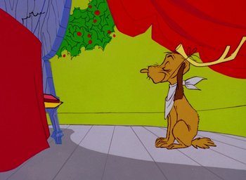 Movie still from “How the Grinch Stole Christmas!” (1966), directed by Ben Washam – A cartoon of a dog sitting in front of a red curtain; Medium shot, Over the shoulder angle