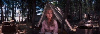 Movie still from “How the West Was Won” (1962), directed by George Marshall – A woman sitting in front of a teepee in the woods; Close Up shot, High angle