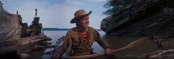 Movie still from “How the West Was Won” (1962), directed by George Marshall – A man wearing a cowboy hat while sitting in a canoe; Medium shot, Low angle
