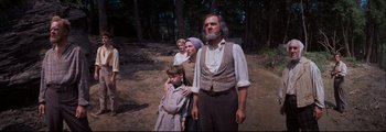 Movie still from “How the West Was Won” (1962), directed by George Marshall – An old man and two women and a boy standing in the dirt; Medium shot, Low angle