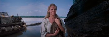 Movie still from “How the West Was Won” (1962), directed by George Marshall – A beautiful woman holding a fur coat near a body of water; Close Up shot, Low angle