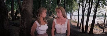 Movie still from “How the West Was Won” (1962), directed by George Marshall – Two young women standing next to each other in a forest; Medium shot, Low angle