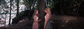 Movie still from “How the West Was Won” (1962), directed by George Marshall – Two young women standing next to each other near a tree; Medium shot, High angle
