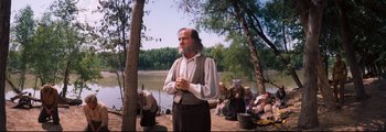 Movie still from “How the West Was Won” (1962), directed by George Marshall – A man with a long beard standing next to a body of water; Medium shot, Over the shoulder angle