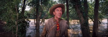 Movie still from “How the West Was Won” (1962), directed by George Marshall – A man wearing a hat and a fur coat in the woods; Medium shot, Low angle