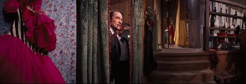 Movie still from “How the West Was Won” (1962), directed by George Marshall – A man standing in front of a curtain with a woman behind him; Medium shot, Over the shoulder angle