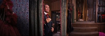 Movie still from “How the West Was Won” (1962), directed by George Marshall – A man in a suit and tie standing in front of a mirror; Medium shot, Low angle