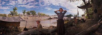 Movie still from “How the West Was Won” (1962), directed by George Marshall – A woman standing next to a man in a cowboy hat; Wide shot, Low angle
