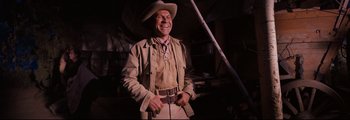 Movie still from “How the West Was Won” (1962), directed by George Marshall – A man wearing a cowboy hat smiling for the camera; Medium shot, Low angle