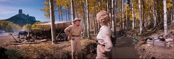 Movie still from “How the West Was Won” (1962), directed by George Marshall – A man and a woman standing in the woods; Wide shot, Low angle