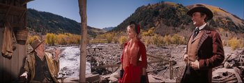 Movie still from “How the West Was Won” (1962), directed by George Marshall – A woman in a red dress standing on a rocky hillside; Wide shot, Low angle