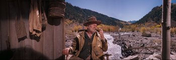 Movie still from “How the West Was Won” (1962), directed by George Marshall – An older man sitting on a chair in the mountains; Medium shot, Low angle