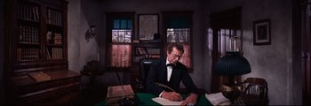 Movie still from “How the West Was Won” (1962), directed by George Marshall – A man sitting at a desk writing on a piece of paper; Medium shot, High angle