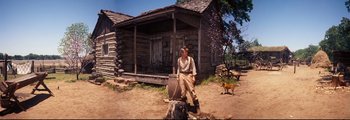 Movie still from “How the West Was Won” (1962), directed by George Marshall – A man standing in front of a log house; Wide shot, Low angle