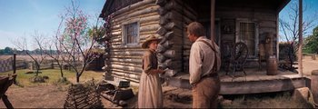Movie still from “How the West Was Won” (1962), directed by George Marshall – A woman and a man standing in front of a log cabin; Wide shot, Low angle