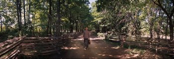 Movie still from “How the West Was Won” (1962), directed by George Marshall – A man walking down a dirt path in a wooded area; Wide shot, High angle