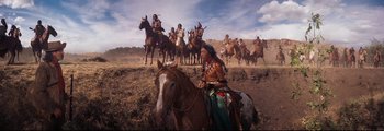 Movie still from “How the West Was Won” (1962), directed by George Marshall – Native americans on horseback in the desert with a crowd of onlookers; Wide shot, Low angle