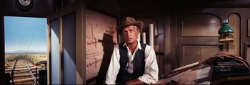Movie still from “How the West Was Won” (1962), directed by George Marshall – A man wearing a hat sitting on a chair; Medium shot, Low angle