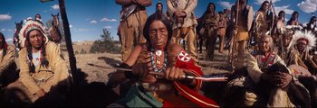 Movie still from “How the West Was Won” (1962), directed by George Marshall – An older native american woman holding a spear; Medium shot, High angle