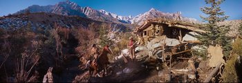 Movie still from “How the West Was Won” (1962), directed by George Marshall – Two men on horses in front of a mountain cabin; Wide shot, Low angle