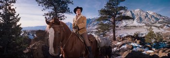 Movie still from “How the West Was Won” (1962), directed by George Marshall – A man riding on the back of a brown horse; Wide shot, Low angle