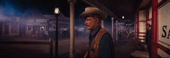 Movie still from “How the West Was Won” (1962), directed by George Marshall – A man wearing a cowboy hat standing next to horses; Medium shot, Over the shoulder angle