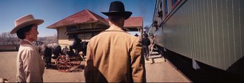 Movie still from “How the West Was Won” (1962), directed by George Marshall – A group of men standing next to each other near train tracks; Wide shot, Over the shoulder angle