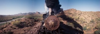 Movie still from “How the West Was Won” (1962), directed by George Marshall – An old steam train is going down the tracks; Wide shot, Low angle