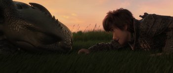 Movie still from “How to Train Your Dragon: The Hidden World” (2019), directed by Dean DeBlois – A boy laying in the grass next to a dinosaur; Close Up shot, High angle
