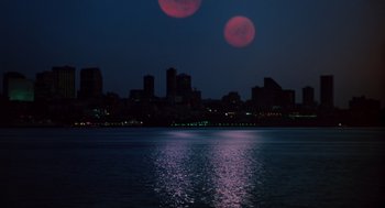 Movie still from “Howard the Duck” (1986), directed by Willard Huyck – A view of a city skyline at night with a full moon in the background; Extreme Wide shot, Low angle