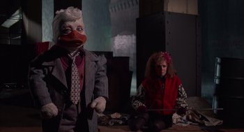 Movie still from “Howard the Duck” (1986), directed by Willard Huyck – Two people dressed up in costumes in a dark room; Medium shot, Low angle