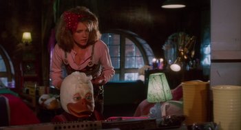 Movie still from “Howard the Duck” (1986), directed by Willard Huyck – A woman standing next to a man with a duck mask on his head; Medium shot, Over the shoulder angle