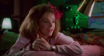 Movie still from “Howard the Duck” (1986), directed by Willard Huyck – A woman in a pink shirt is sitting on a bed; Close Up shot, Low angle