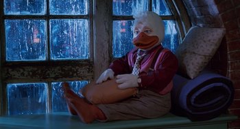 Movie still from “Howard the Duck” (1986), directed by Willard Huyck – A person sitting on a window ledge wearing a duck mask; Medium shot, Low angle